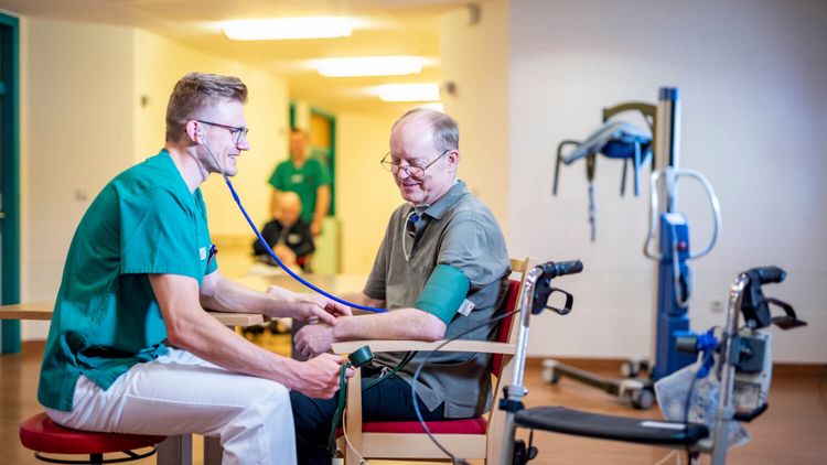 Pflegekraft misst bei einem älteren Patienten den Blutdruck