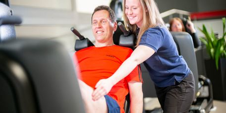 Therapeutin unterstützt Patient bei der Medizinischen Trainingstherapie