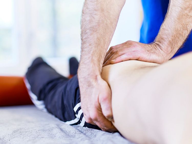 Therapeut massiert Bein eines Patienten