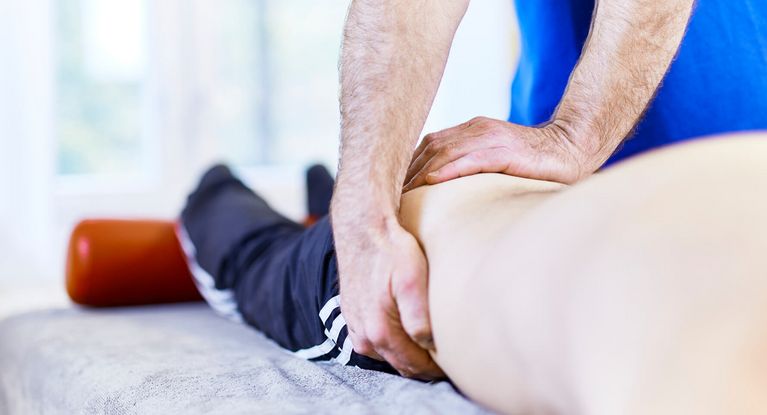 Therapeut massiert Bein eines Patienten