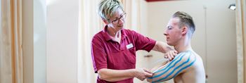 Therapeut versorgt Patienten mit Kinesiotape