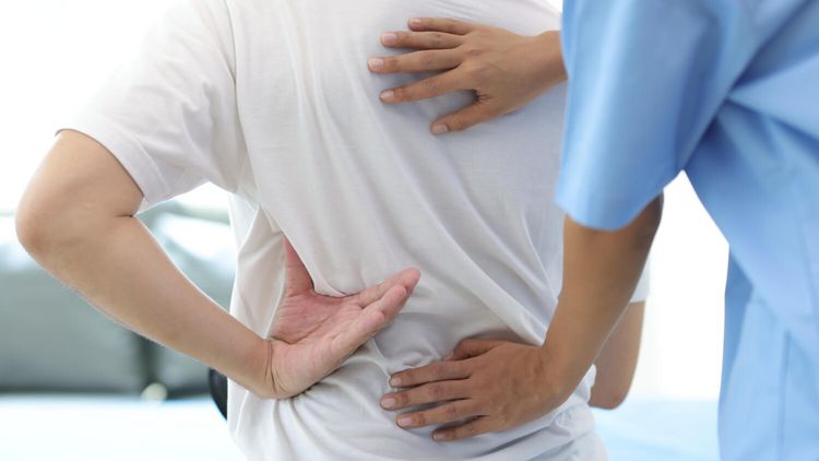 Therapeut behandelt Rücken eines Patienten