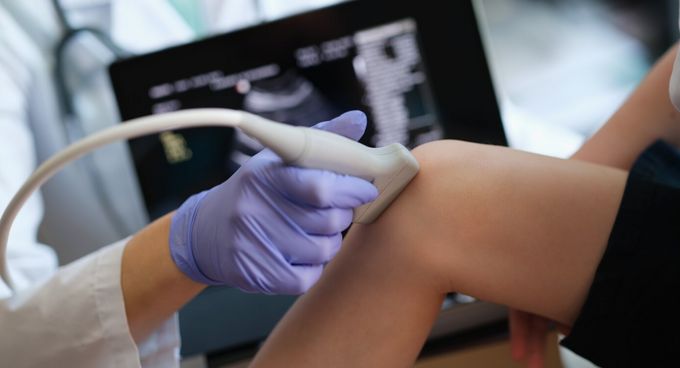 Arzt untersucht Kniegelenk mit Ultraschall